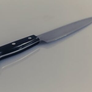 A detailed view of a stainless steel kitchen knife reflecting light on a white surface.